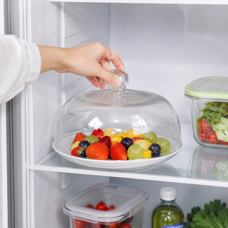 Cloche en verre réutilisable protégeant une assiette de fruits au réfrigérateur
