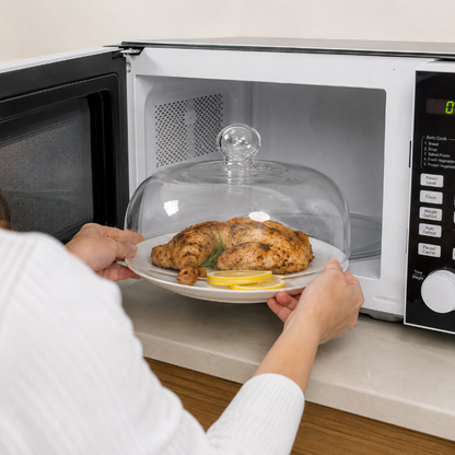 Assiette de poulet protégée par une cloche micro onde en verre dans le micro-ondes