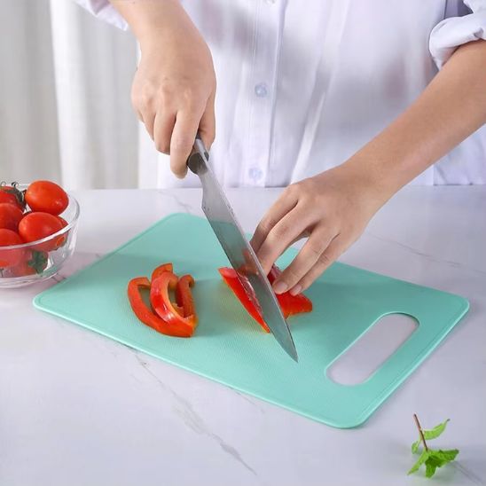 planche a decouper turquoise femme qui decoupe un poivron